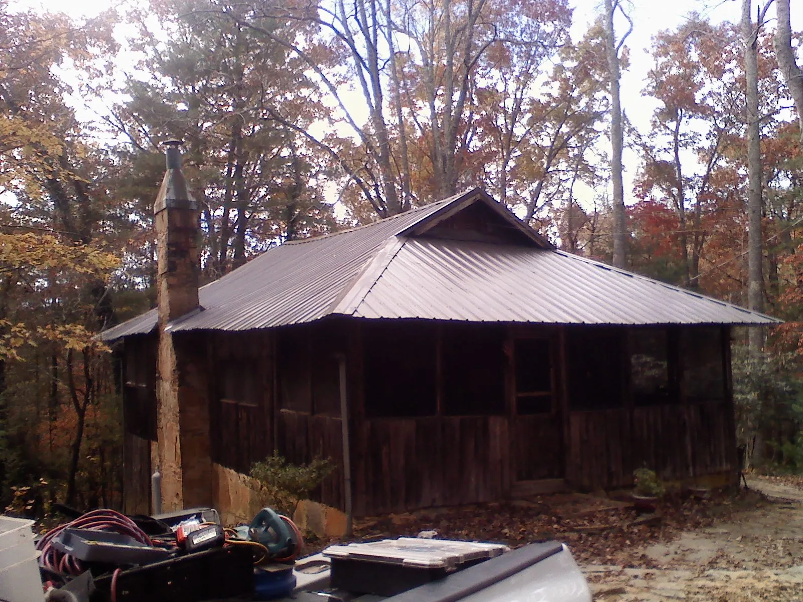 Brown metal hip roof on an old cabin with a stone chimney in Palmetto